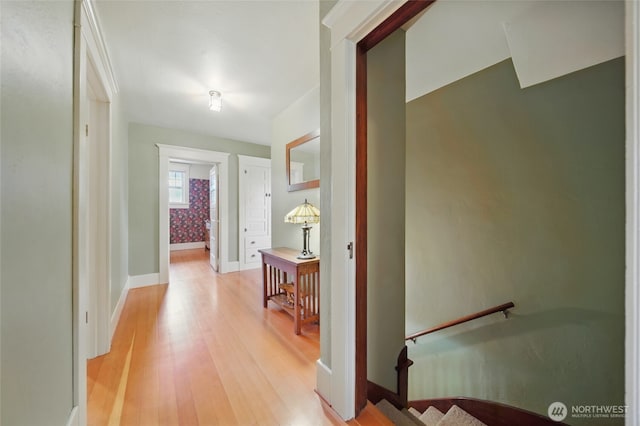corridor featuring an upstairs landing, light wood-type flooring, and baseboards