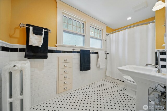 bathroom with tile walls, a shower with curtain, wainscoting, toilet, and tile patterned flooring