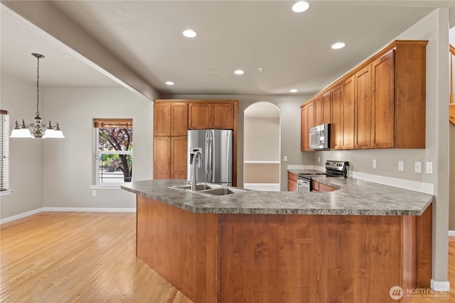 2149 Inglewood Dr, East Wenatchee, WA 98802 - kitchen featuring stainless steel appliances, light wood-style flooring, arched walkways, brown cabinets, and recessed lighting