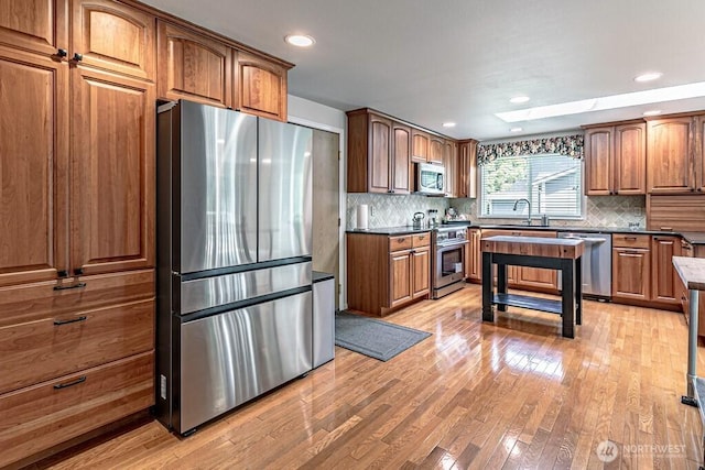 2117 130th Dr NE, Lake Stevens, WA 98258 - kitchen featuring stainless steel appliances, light wood-style floors, tasteful backsplash, a sink, and brown cabinets