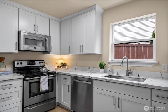 12570 SE 295th St, Auburn, WA 98092 - kitchen featuring appliances with stainless steel finishes, a sink, white cabinetry, and light stone countertops