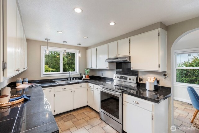 2016 Marine Dr, Bremerton, WA 98312 - kitchen featuring stainless steel range with electric cooktop, a sink, under cabinet range hood, stone tile floors, and healthy amount of natural light