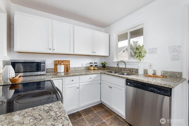 kitchen featuring appliances with stainless steel finishes, a sink, white cabinetry, and light stone countertops