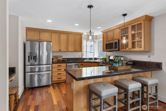 403 21st Ave, Seattle, WA 98122 - kitchen featuring stainless steel appliances, a peninsula, glass insert cabinets, decorative light fixtures, and wood-type flooring