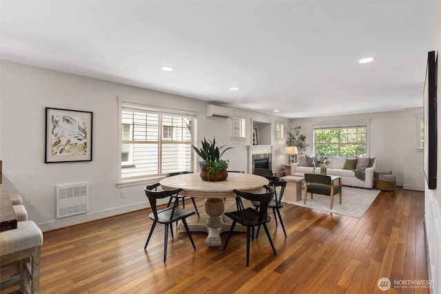 403 21st Ave, Seattle, WA 98122 - dining area with a wall unit AC, a glass covered fireplace, hardwood / wood-style flooring, recessed lighting, and baseboards