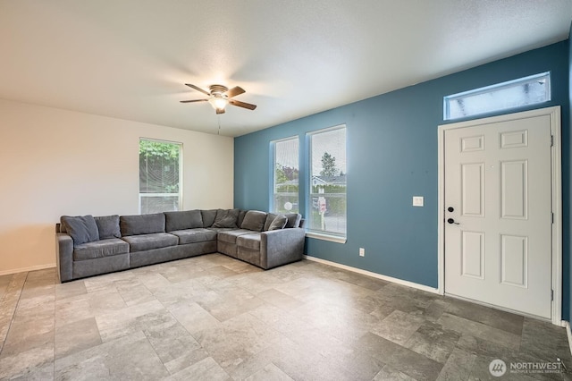 living room with a ceiling fan, plenty of natural light, and baseboards