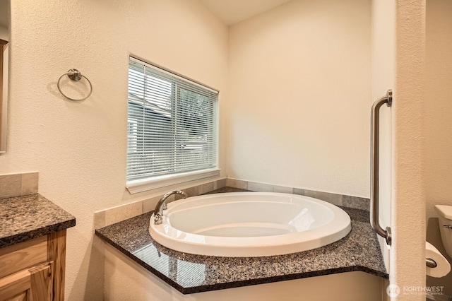 bathroom with a bath, vanity, and a textured wall