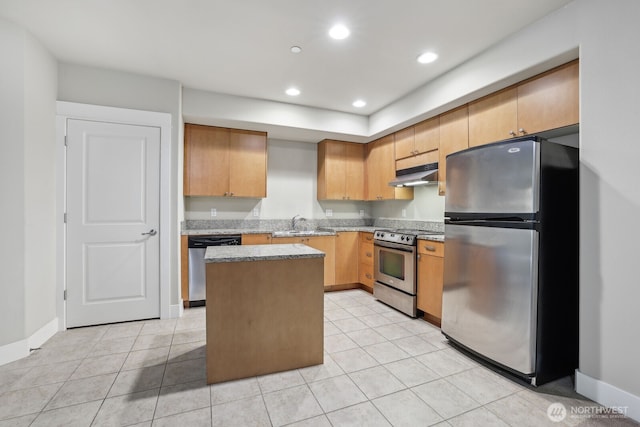 kitchen featuring appliances with stainless steel finishes, under cabinet range hood, a center island, light stone counters, and baseboards