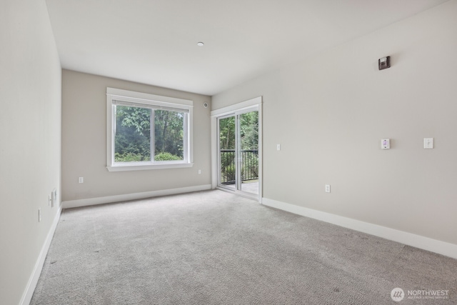 unfurnished room featuring light carpet and baseboards