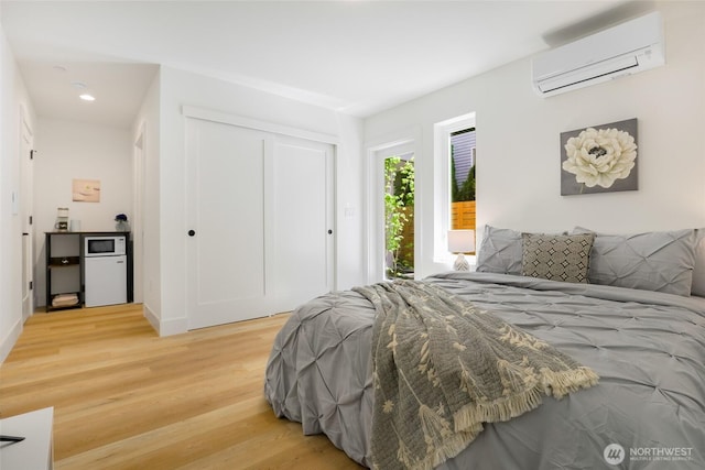 bedroom with an AC wall unit, light wood-style floors, a closet, and recessed lighting