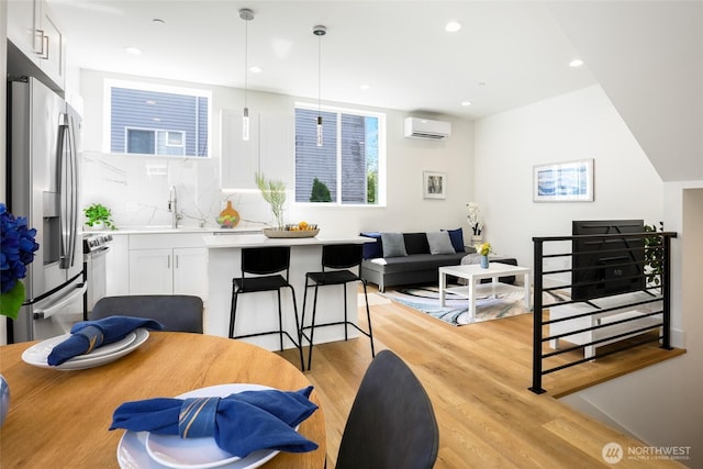 dining room featuring a wall unit AC, light wood-style floors, recessed lighting, and plenty of natural light