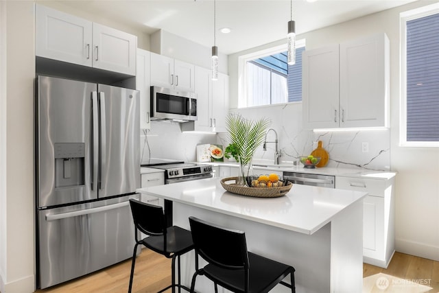 kitchen featuring stainless steel appliances, a sink, light countertops, white cabinets, and light wood-style flooring