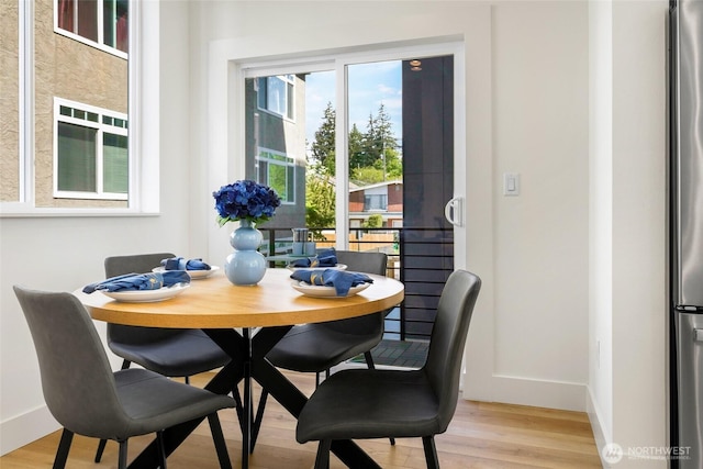 dining space featuring light wood finished floors and baseboards