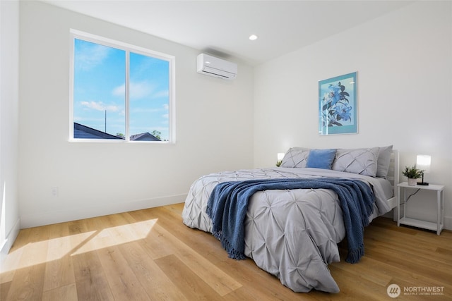 bedroom featuring a wall mounted air conditioner, baseboards, light wood-style flooring, and recessed lighting
