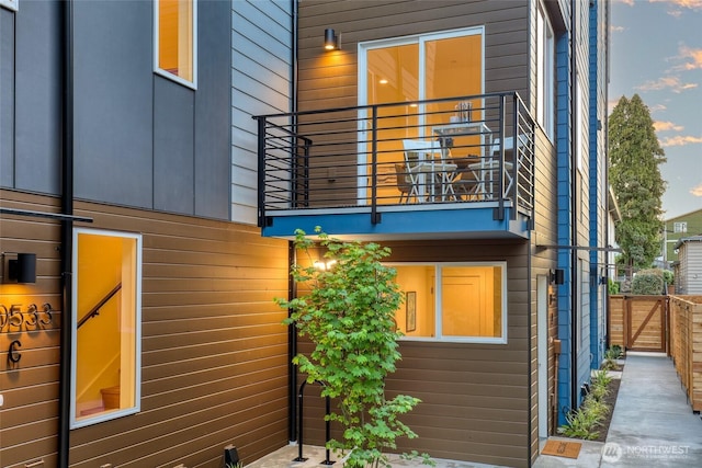 rear view of property featuring a balcony and fence