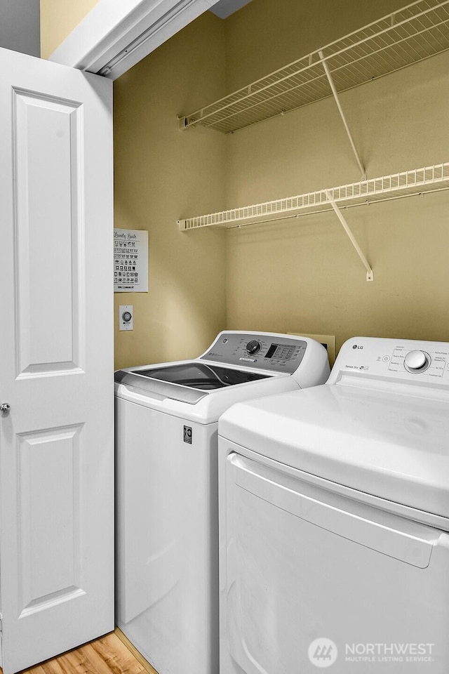 clothes washing area featuring washing machine and clothes dryer and light wood-type flooring