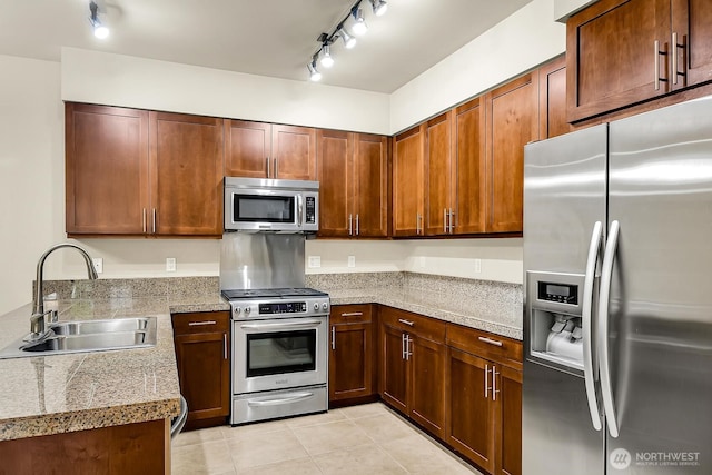 kitchen with stainless steel appliances, a sink, rail lighting, and tile counters