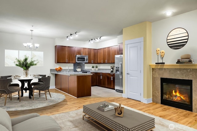 living area with light wood finished floors, a premium fireplace, a chandelier, and baseboards