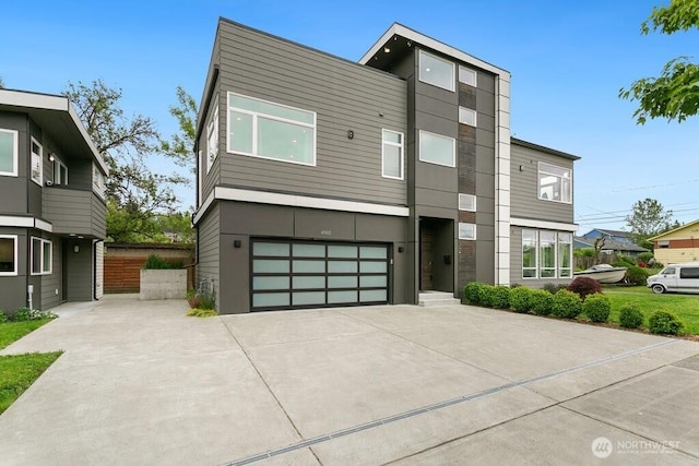 modern home with concrete driveway, an attached garage, and fence