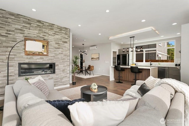 living room featuring baseboards, wood finished floors, recessed lighting, and a wall mounted air conditioner