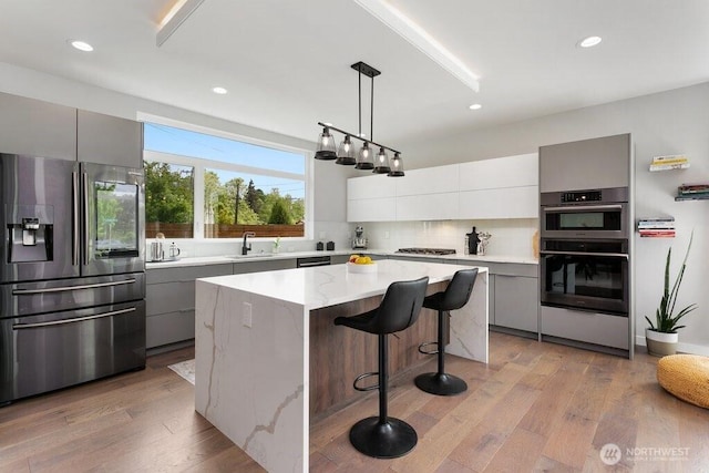 kitchen with appliances with stainless steel finishes, gray cabinetry, a sink, modern cabinets, and decorative backsplash