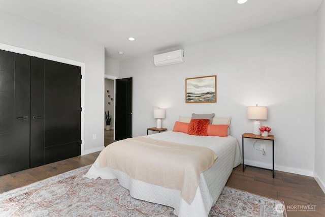 bedroom with a wall unit AC, wood finished floors, recessed lighting, and baseboards