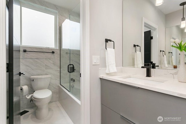 bathroom with toilet, vanity, and shower / bath combination with glass door