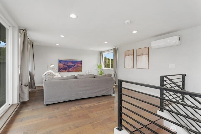 living room with a wall mounted air conditioner, wood finished floors, recessed lighting, and baseboards