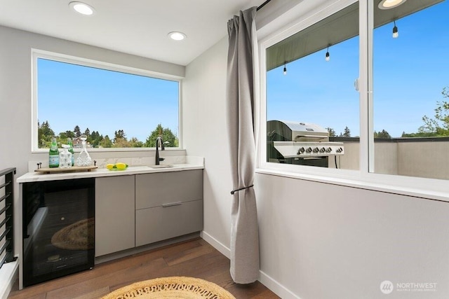 bathroom featuring wine cooler, wood finished floors, a sink, baseboards, and recessed lighting