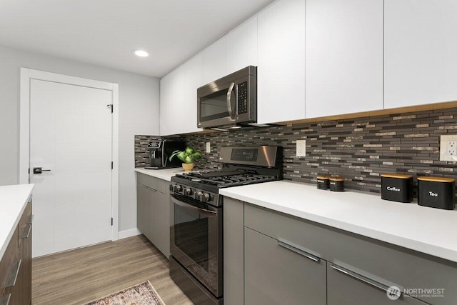 kitchen with stainless steel appliances, gray cabinetry, decorative backsplash, light countertops, and recessed lighting