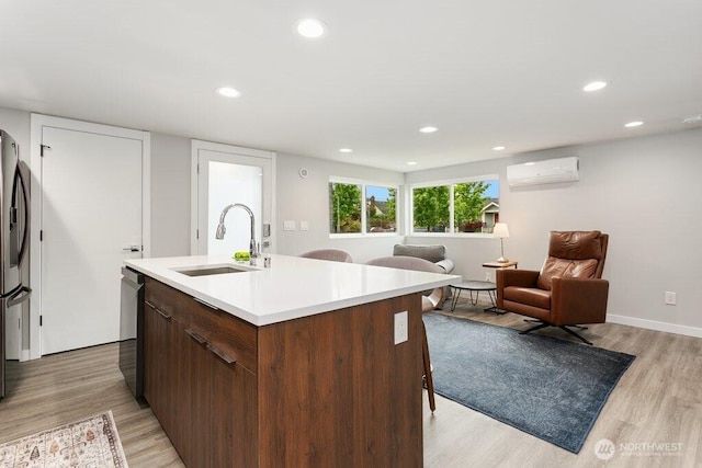 kitchen featuring a sink, an AC wall unit, light wood-style flooring, light countertops, and recessed lighting