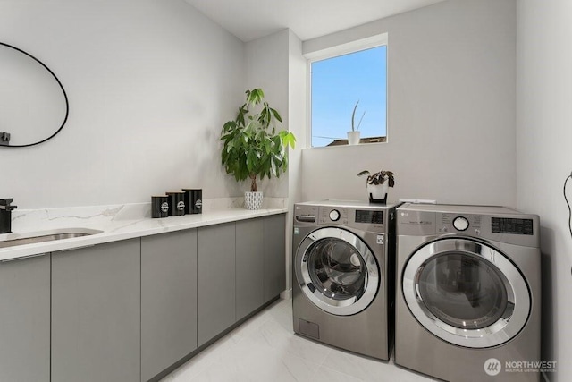 laundry room with washing machine and clothes dryer, cabinet space, and light marble finish flooring