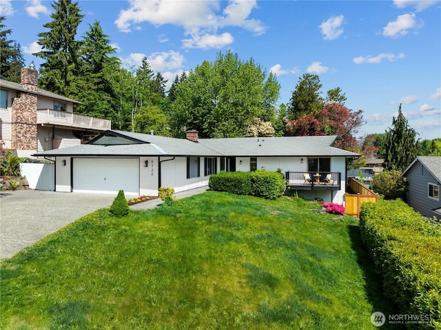 view of front facade featuring concrete driveway, an attached garage, a front yard, and a chimney