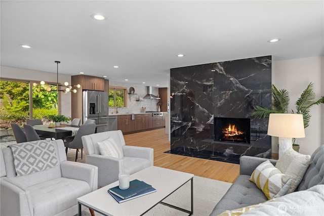 living area featuring recessed lighting, a chandelier, light wood-type flooring, and a high end fireplace