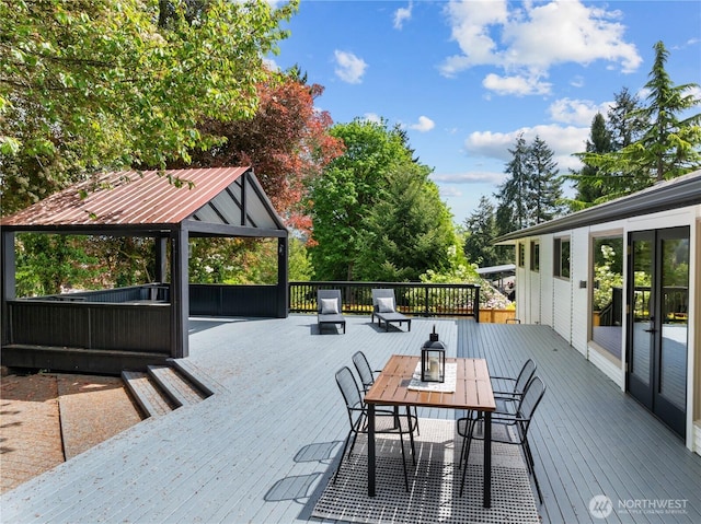 wooden terrace featuring a gazebo and outdoor dining area