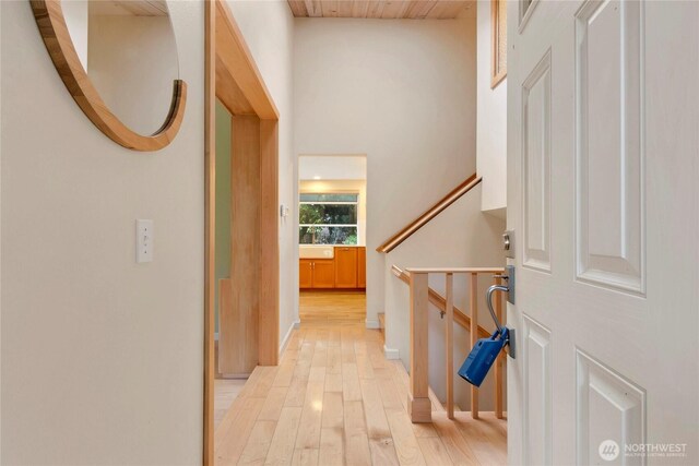 hall featuring light wood-style flooring, stairway, and wooden ceiling