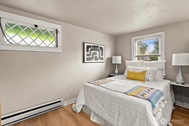 508 N 95th St, Seattle, WA 98103 - bedroom with a baseboard radiator, multiple windows, wood finished floors, and a textured ceiling