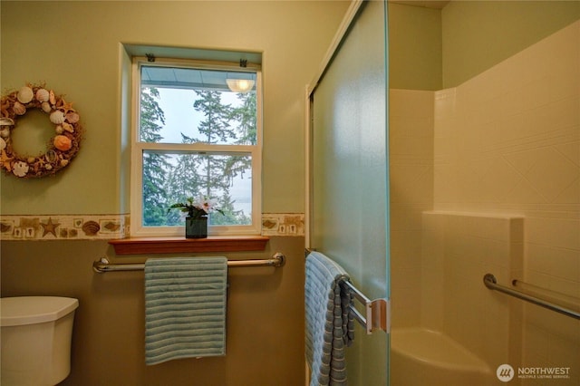 362 N Sunrise Blvd, Camano Island, WA 98282 - bathroom with a shower with shower door, toilet, a wainscoted wall, and tile walls