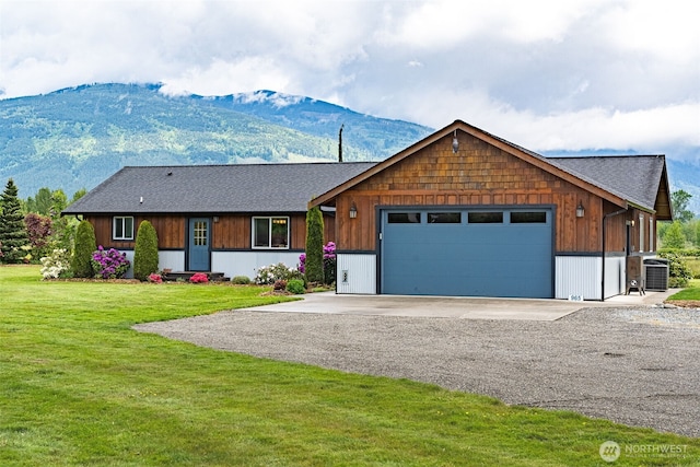 view of front of property featuring an attached garage, a mountain view, driveway, central AC, and a front lawn