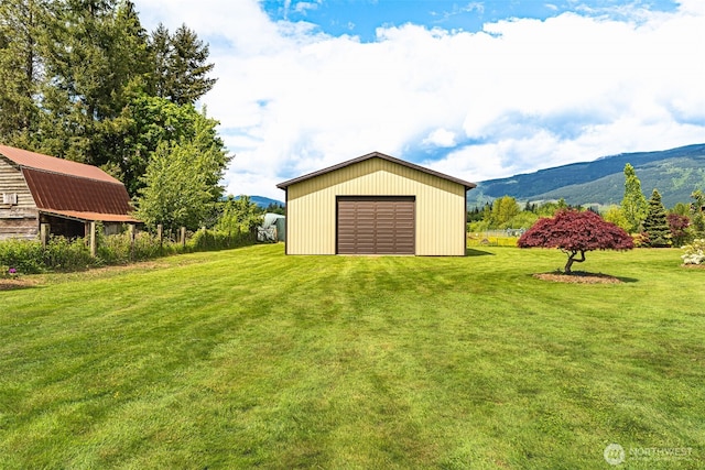 view of green lawn featuring an outdoor structure, a mountain view, and a garage