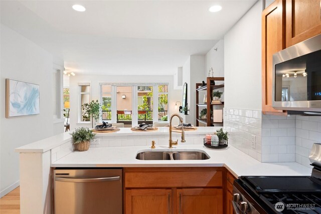 2607 Western Ave Unit 202, Seattle, WA 98121 - kitchen with appliances with stainless steel finishes, a sink, light countertops, a peninsula, and decorative backsplash