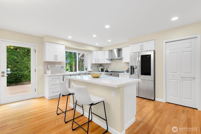 23322 SE 26th Pl, Sammamish, WA 98075 - kitchen with stainless steel appliances, wall chimney range hood, a kitchen breakfast bar, tasteful backsplash, and a center island