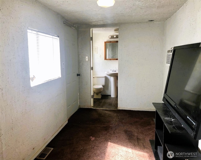 953 E Ash St, Othello, WA 99344 - bathroom featuring a textured wall, toilet, a textured ceiling, baseboards, and a sink