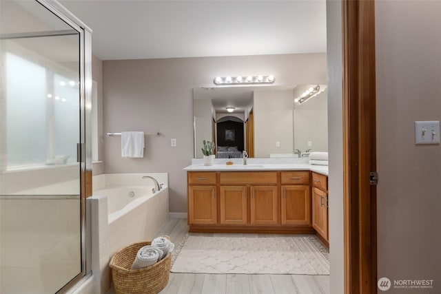 full bath with a bath, a stall shower, double vanity, and wood finished floors