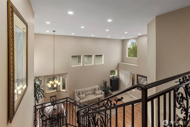 stairway with a chandelier, recessed lighting, wood finished floors, and a towering ceiling