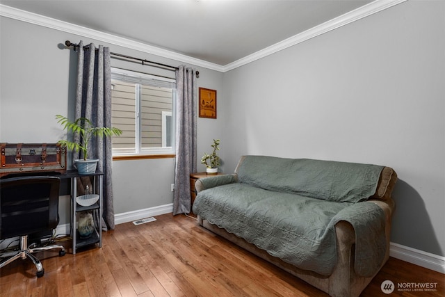 living area featuring baseboards, hardwood / wood-style floors, ornamental molding, and a desk