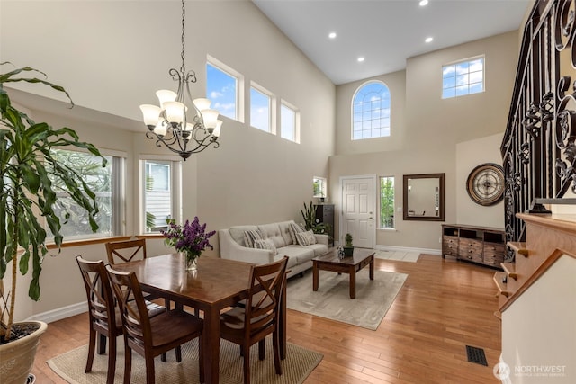 dining area featuring a chandelier, a high ceiling, recessed lighting, light wood-type flooring, and baseboards