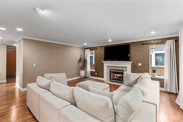 living area featuring recessed lighting, a tiled fireplace, baseboards, ornamental molding, and light wood finished floors