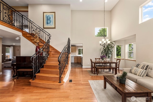 living room with a high ceiling, light wood finished floors, stairs, healthy amount of natural light, and recessed lighting