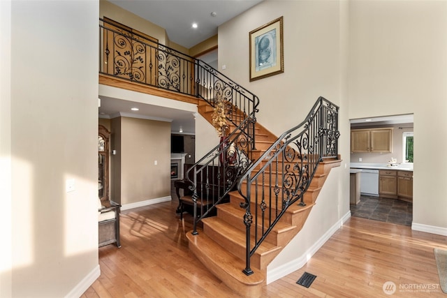 stairway featuring a high ceiling, wood finished floors, baseboards, and recessed lighting